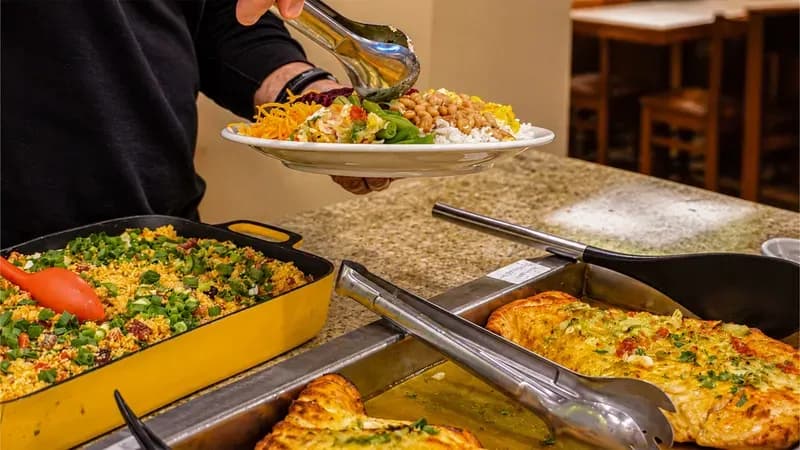 Cliente servindo-se no buffet quente do Fogão de Ouro